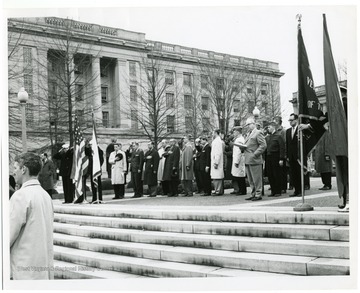 A group of men salute the American flag at a ceremony honoring World War II veterans and the U.S.S. West Virginia battleship.