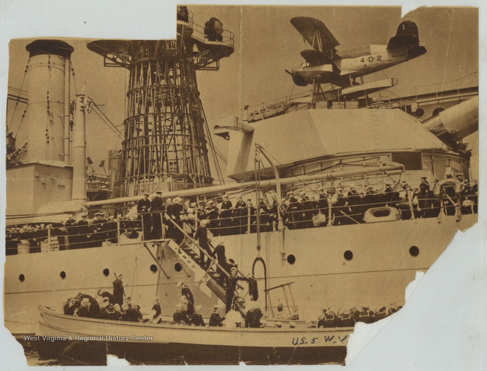 Sailors and Naval officers fill the battleship's deck. 