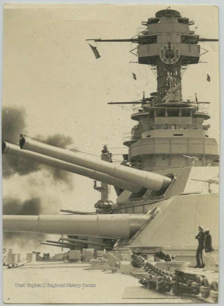 Two sailors on the deck observe the gunfire.