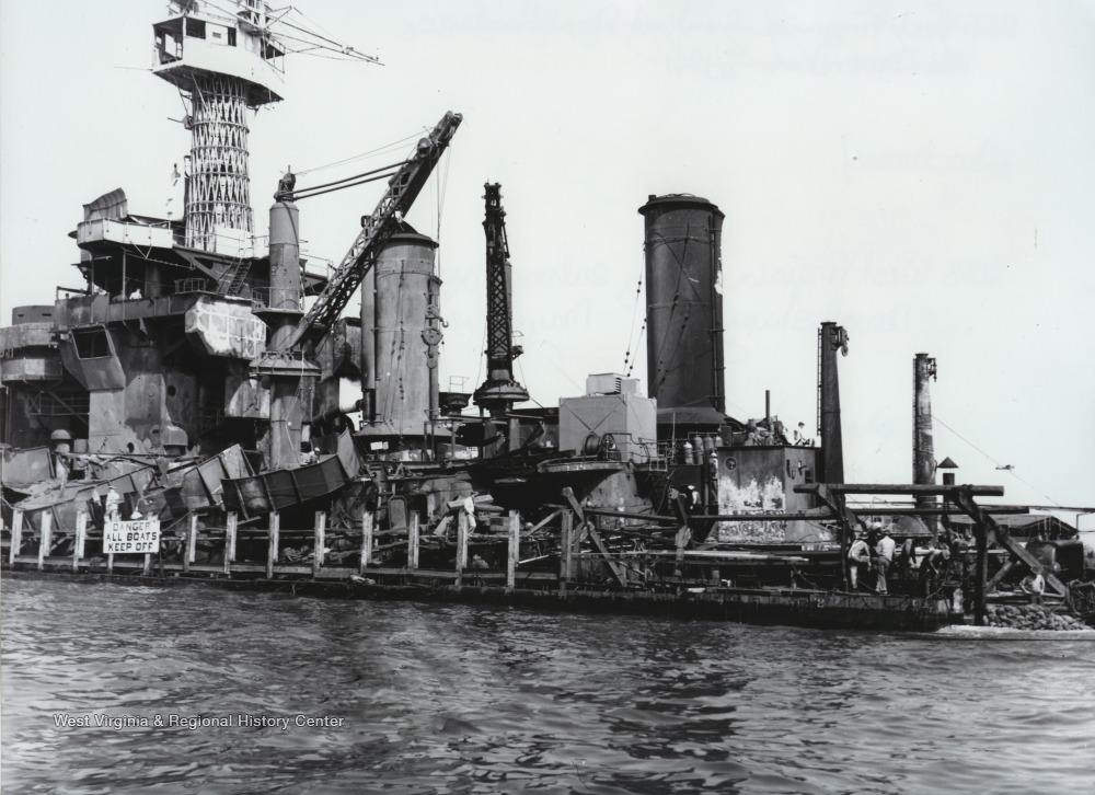 The U.S.S. West Virginia looks battered and wounded while docked at the naval shipyard. The "Wee Vee" was hit by nine bombs and torpedoes by the Japanese warplanes during the December 7th attack. 