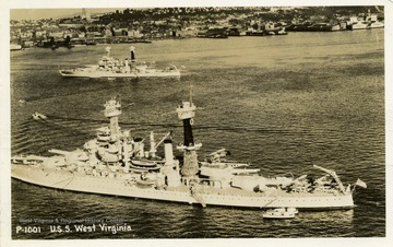 Postcard of the U.S.S. West Virginia at sea outside of a city. The photograph was taken before 1941.