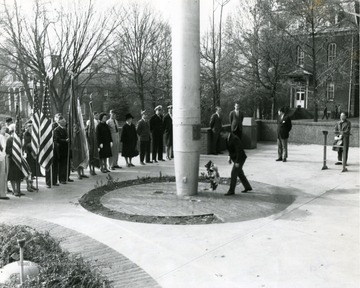 A wreath is placed by the mast of the U.S.S. West Virginia in Memorial Plaza. Martin hall is pictured in the background on the right. Elizabeth Moore Hall can be seen in the background on the left. 