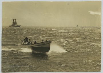 A boat speeds across the sea while the U.S.S. West Virginia lurks in the background. 
