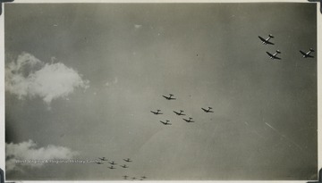 A fleet of U.S. bomber airplanes fly across the sky. The photograph comes from a U.S.S. West Virginia Scrapbook. 
